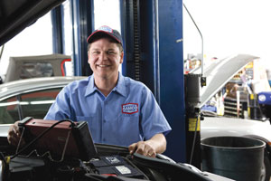 Image of Smiling AAMCO Mechanic giving an Engine a Tuneup